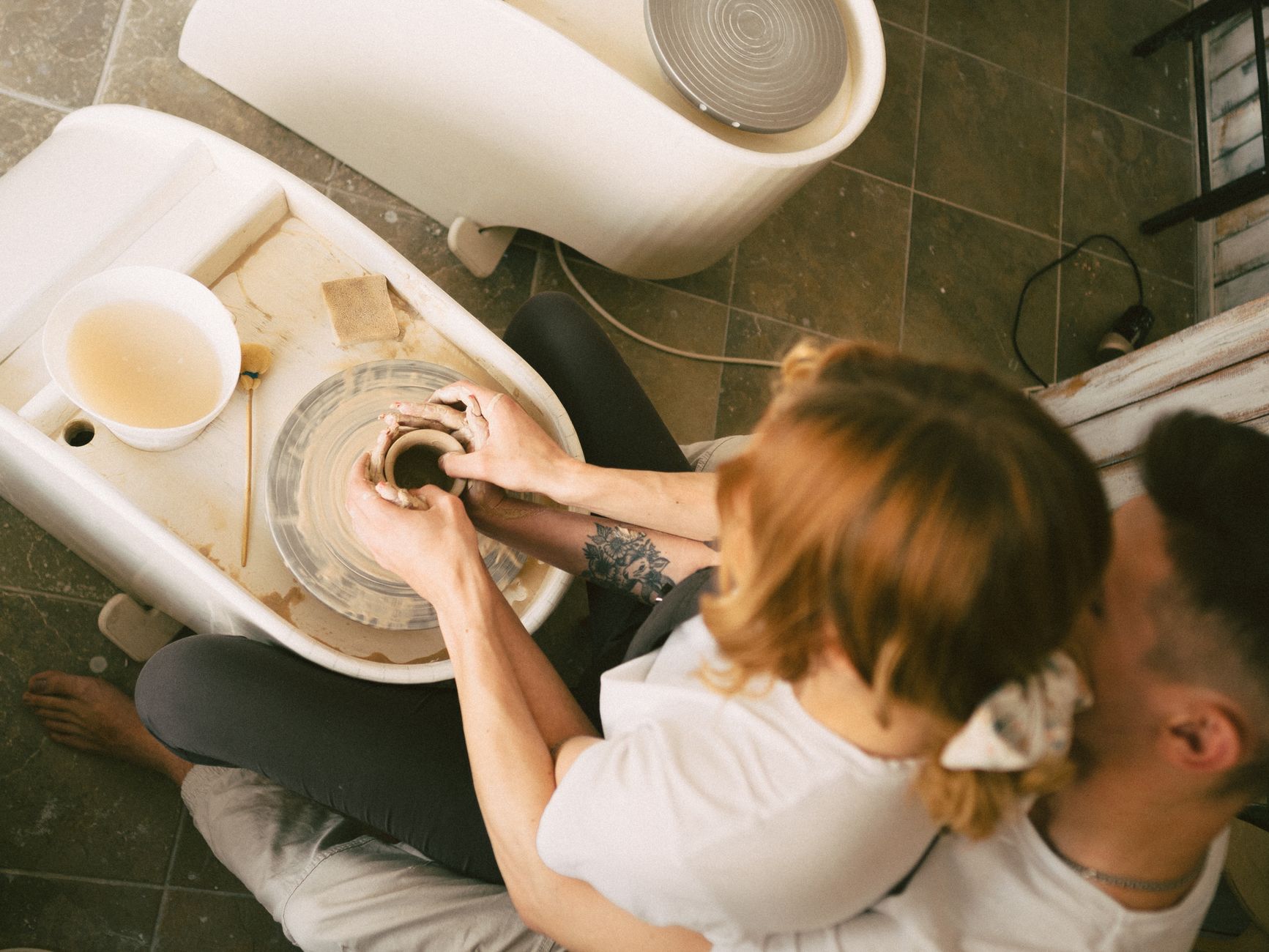 A couple intimately engaged in learning pottery together from a high angle view.