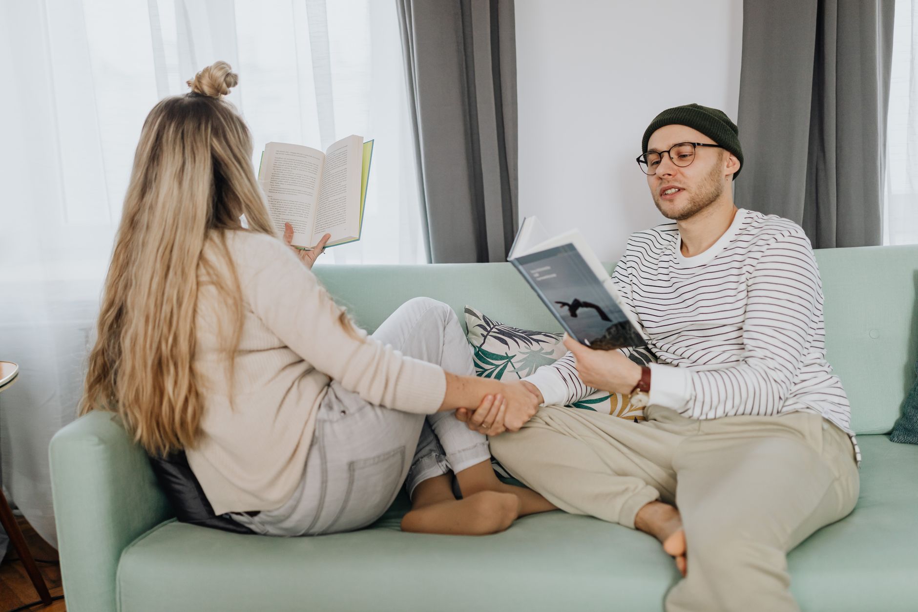 A couple enjoys a relaxing moment reading books together on a cozy sofa.
