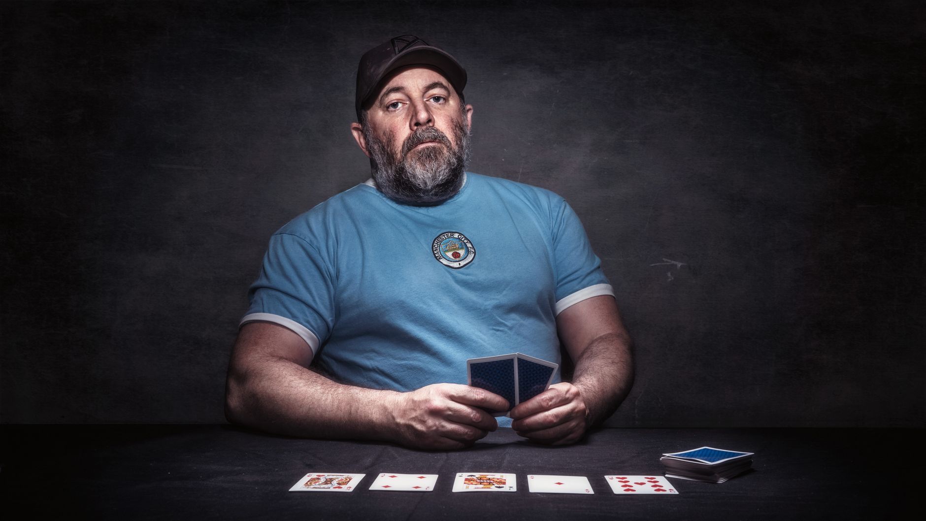 Adult male in Manchester playing poker indoors, wearing a blue shirt.