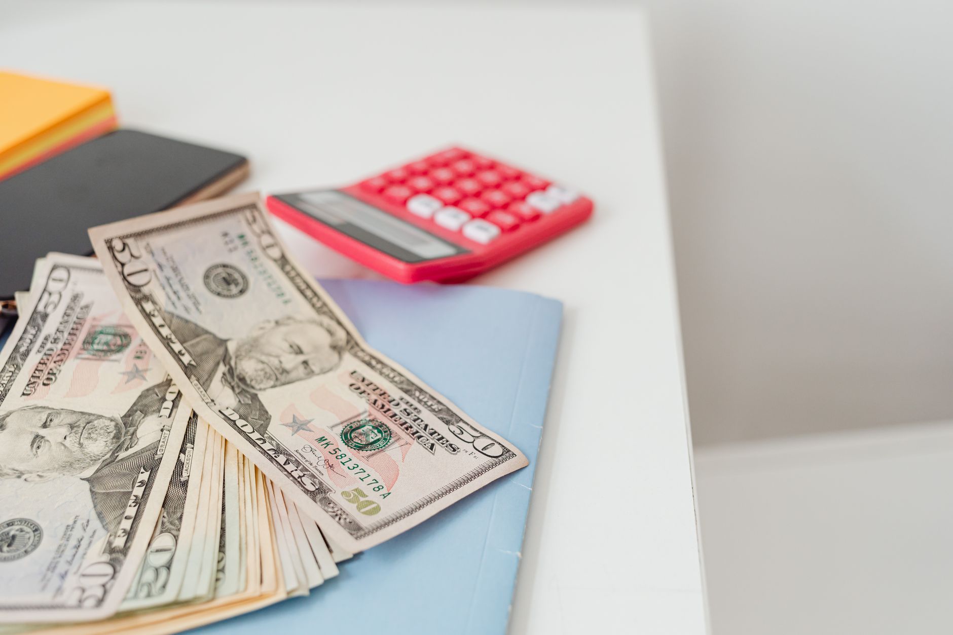 Notebooks, cash, and a calculator on a desk