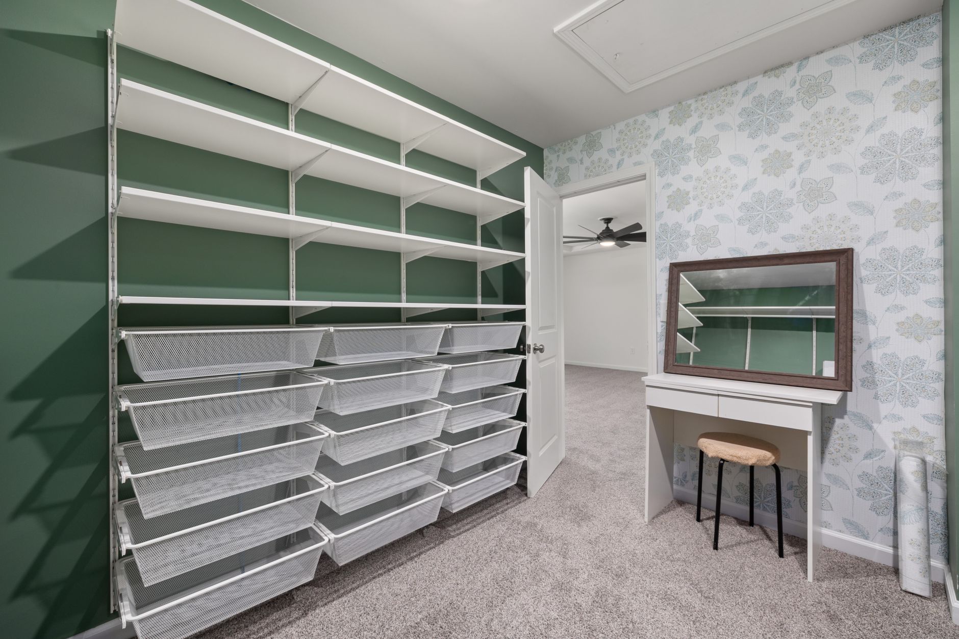 Spacious walk-in closet with built-in shelving, storage bins, and a vanity desk with mirror.