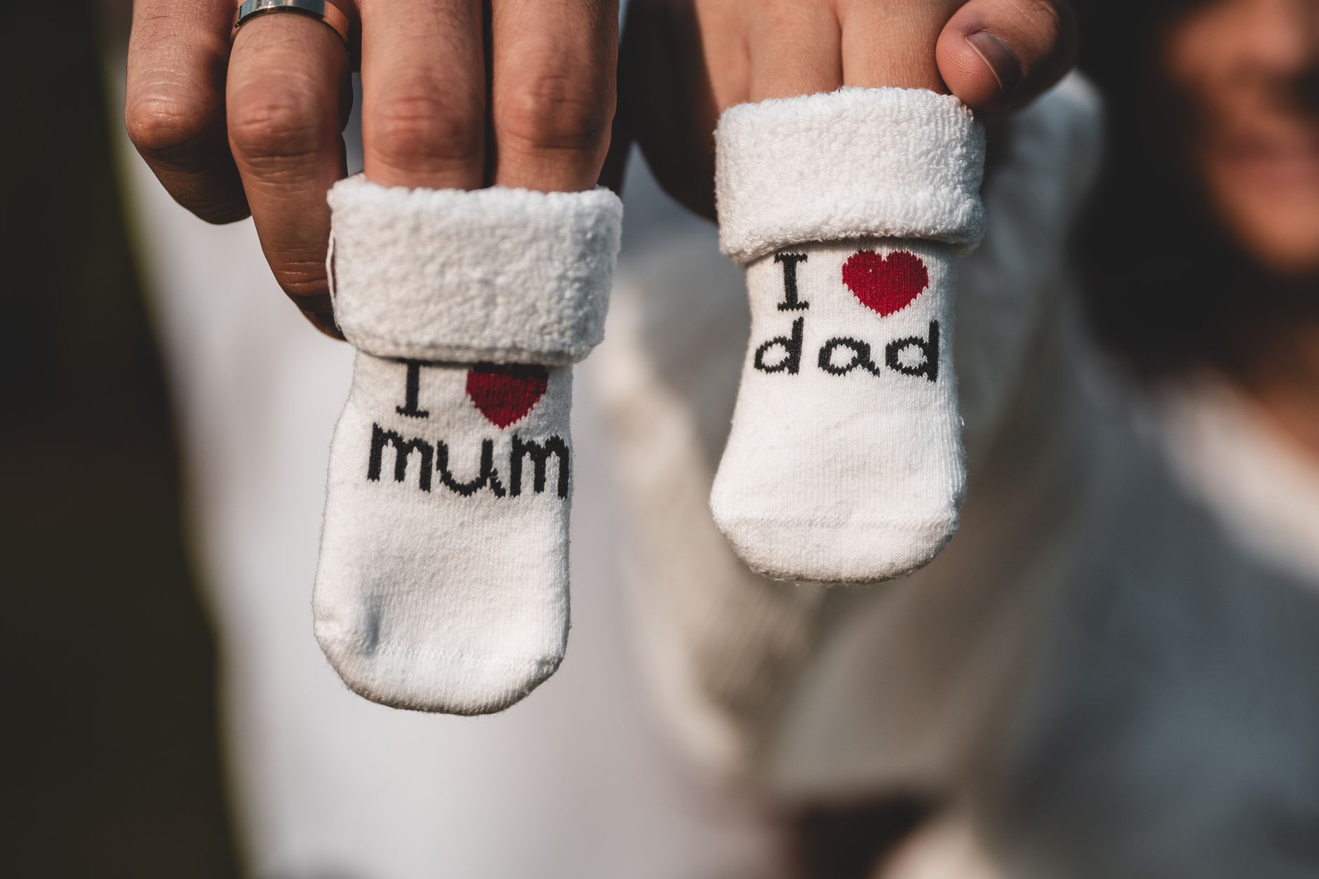 Adorable baby socks with 'I love mum' and 'I love dad' messages held by parents' hands. Perfect for family themes.