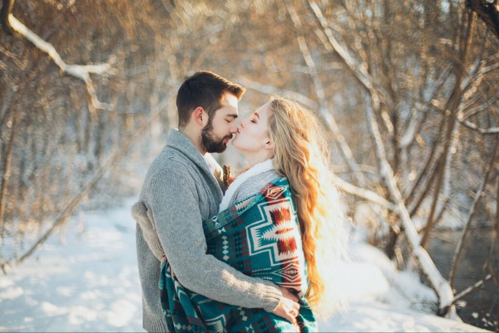 Couple embracing and kissing outdoors in the snow
