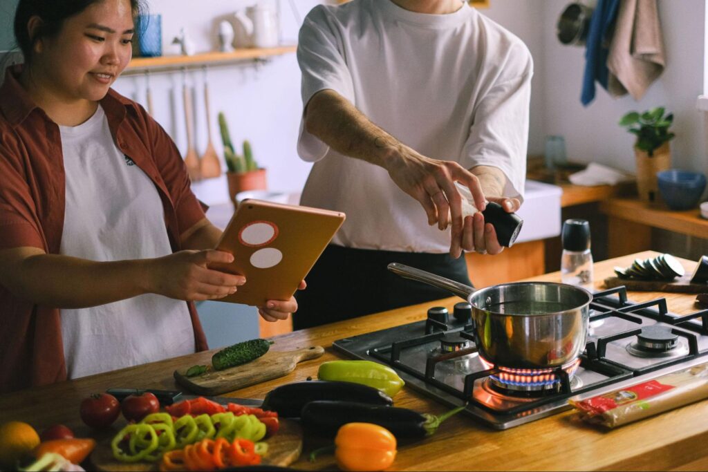 Couple cooking a meal together in the kitchen with fresh vegetables