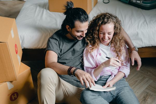Happy couple planning together with a notebook surrounded by moving boxes