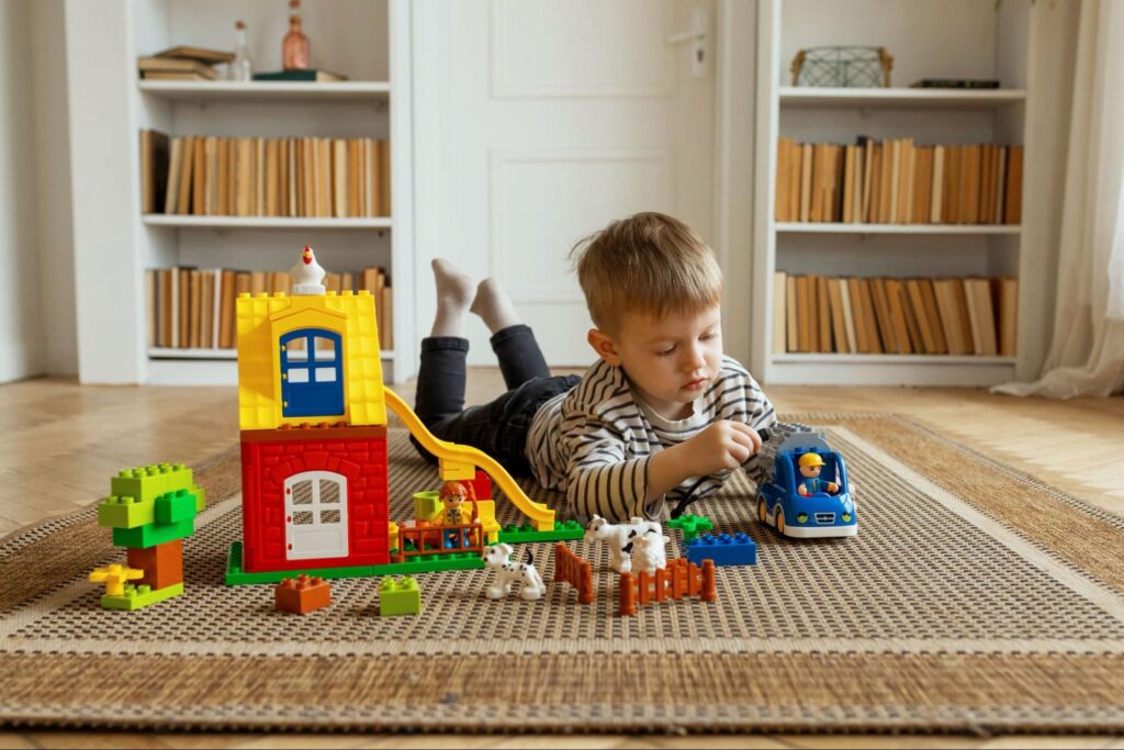 Young child playing with colorful building blocks and toy animals on the floor