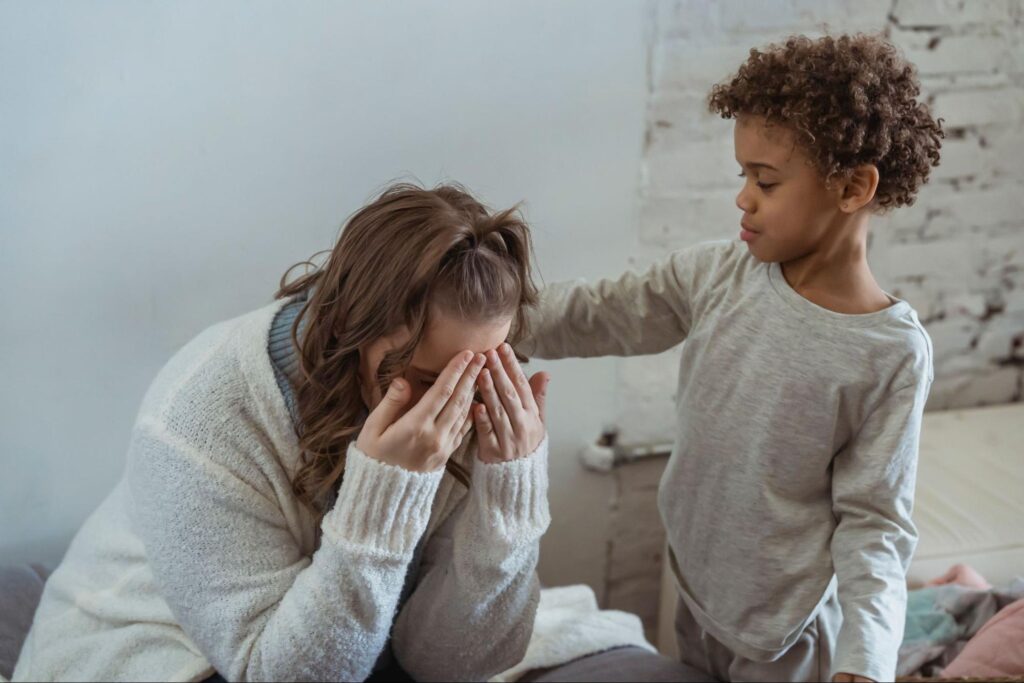 Young boy comforting a distressed adult by placing a hand on her shoulder