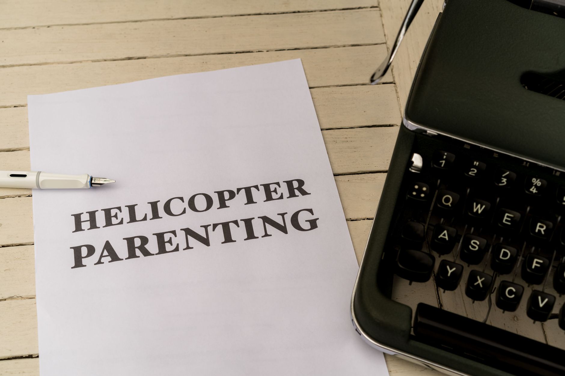 Paper with 'Helicopter Parenting' text next to a typewriter and pen