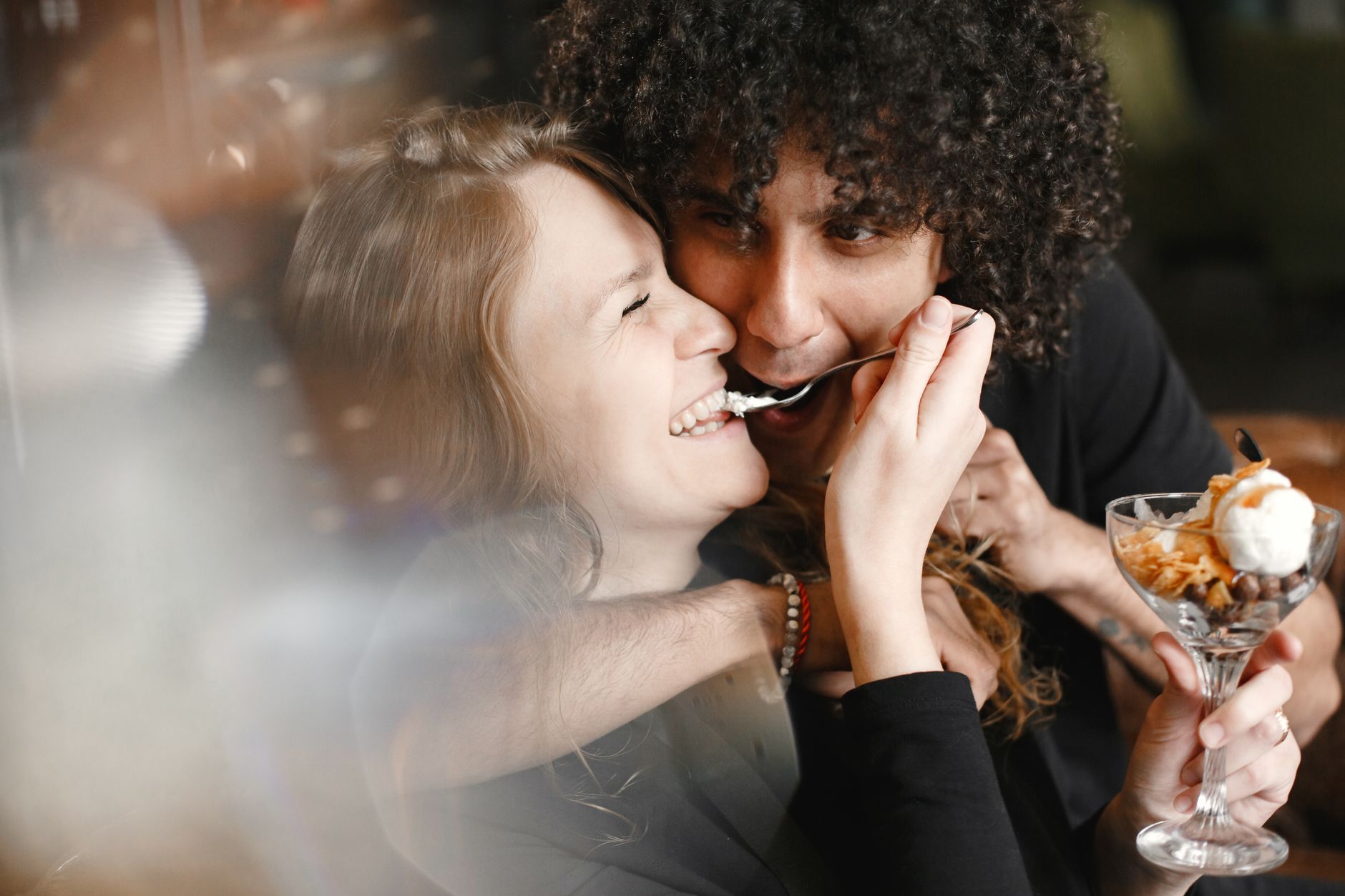 Happy couple laughing and enjoying dessert together, showcasing love and togetherness.