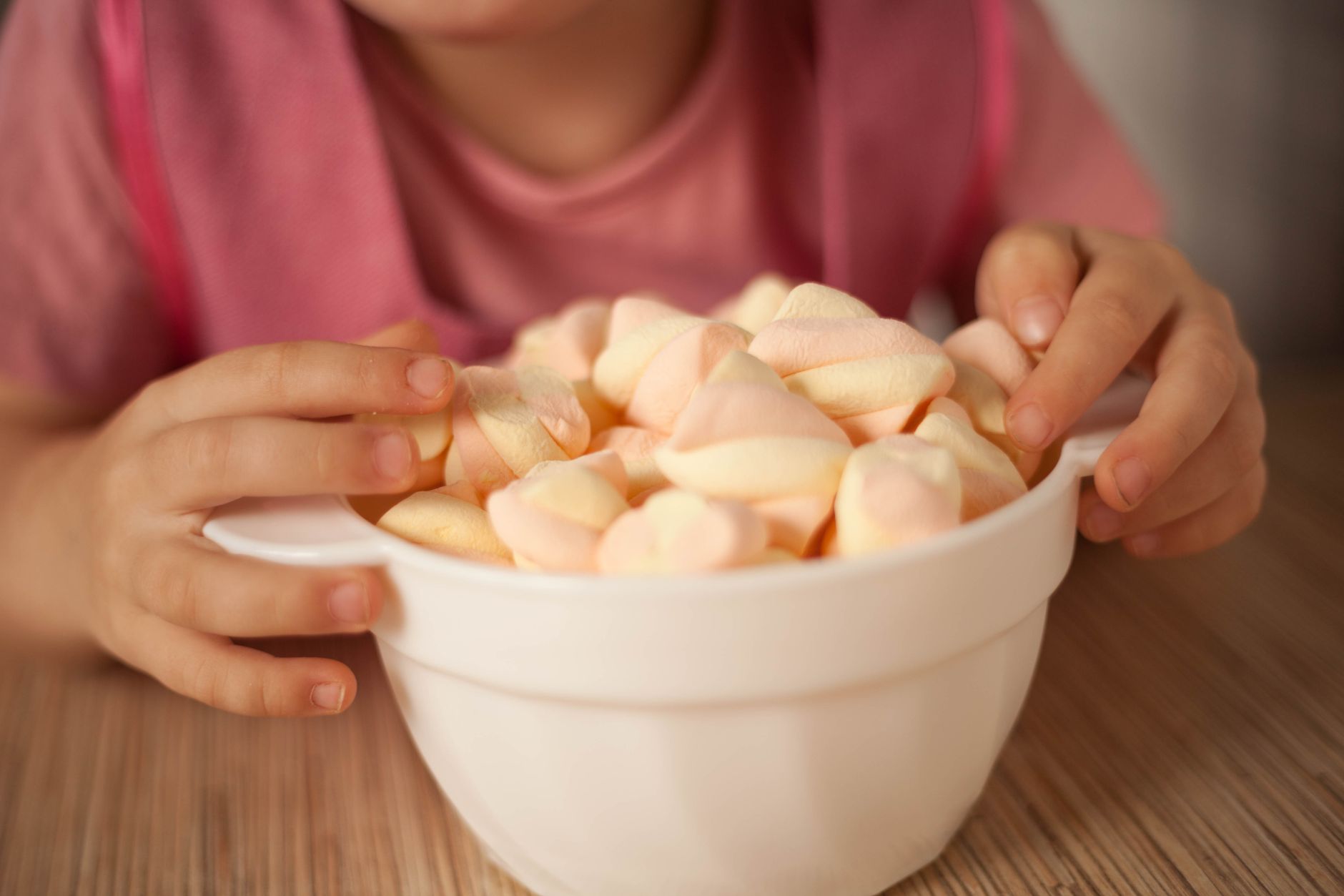Close-up of a child with a bowl of colorful marshmallows, highlighting a playful snack moment.