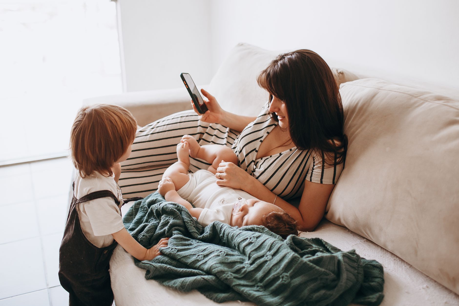 A mother relaxes on a sofa with her two children, enjoying quality time together.