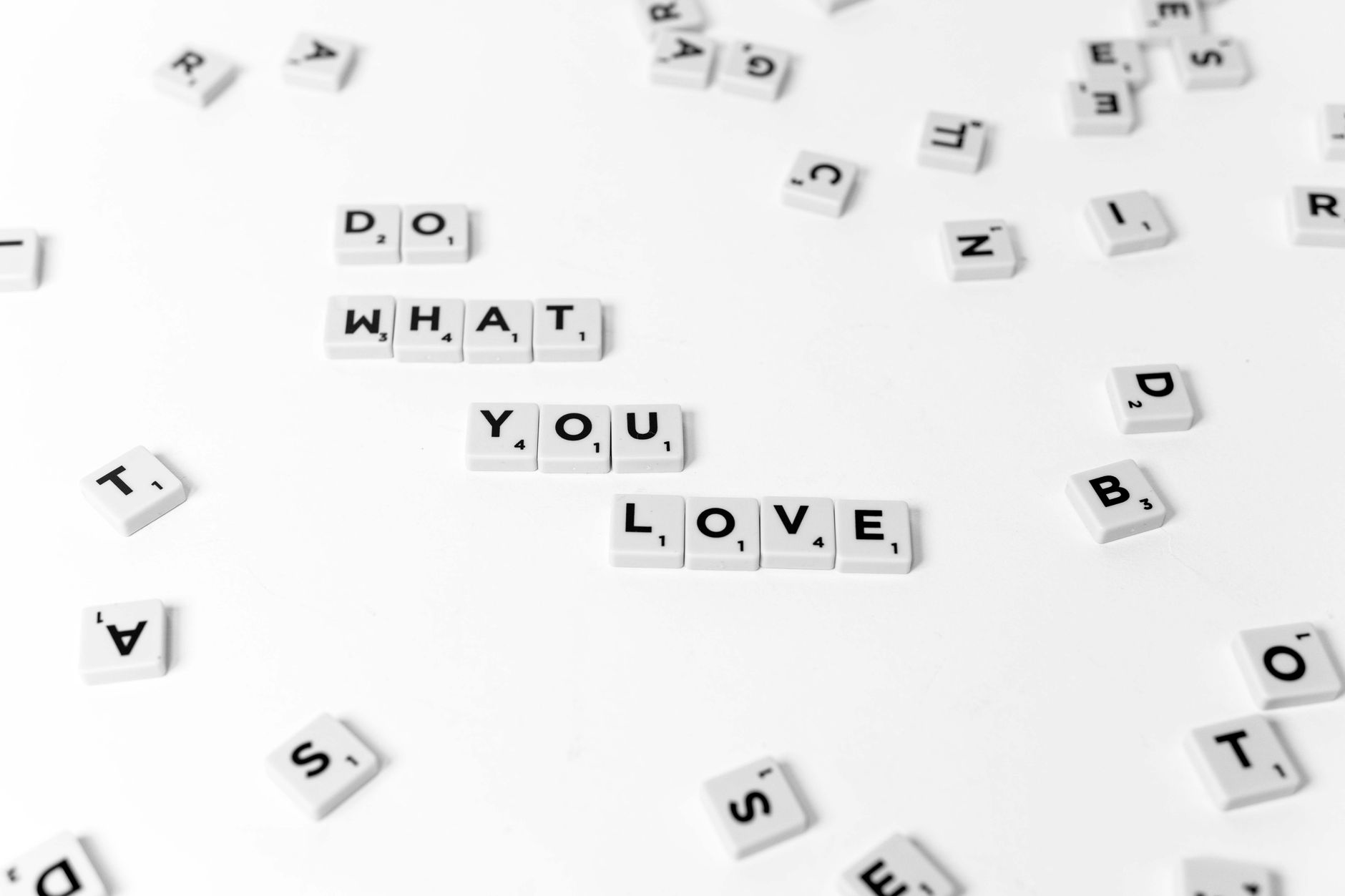 Minimalist photo of scrabble tiles spelling 'DO WHAT YOU LOVE' on a white background.