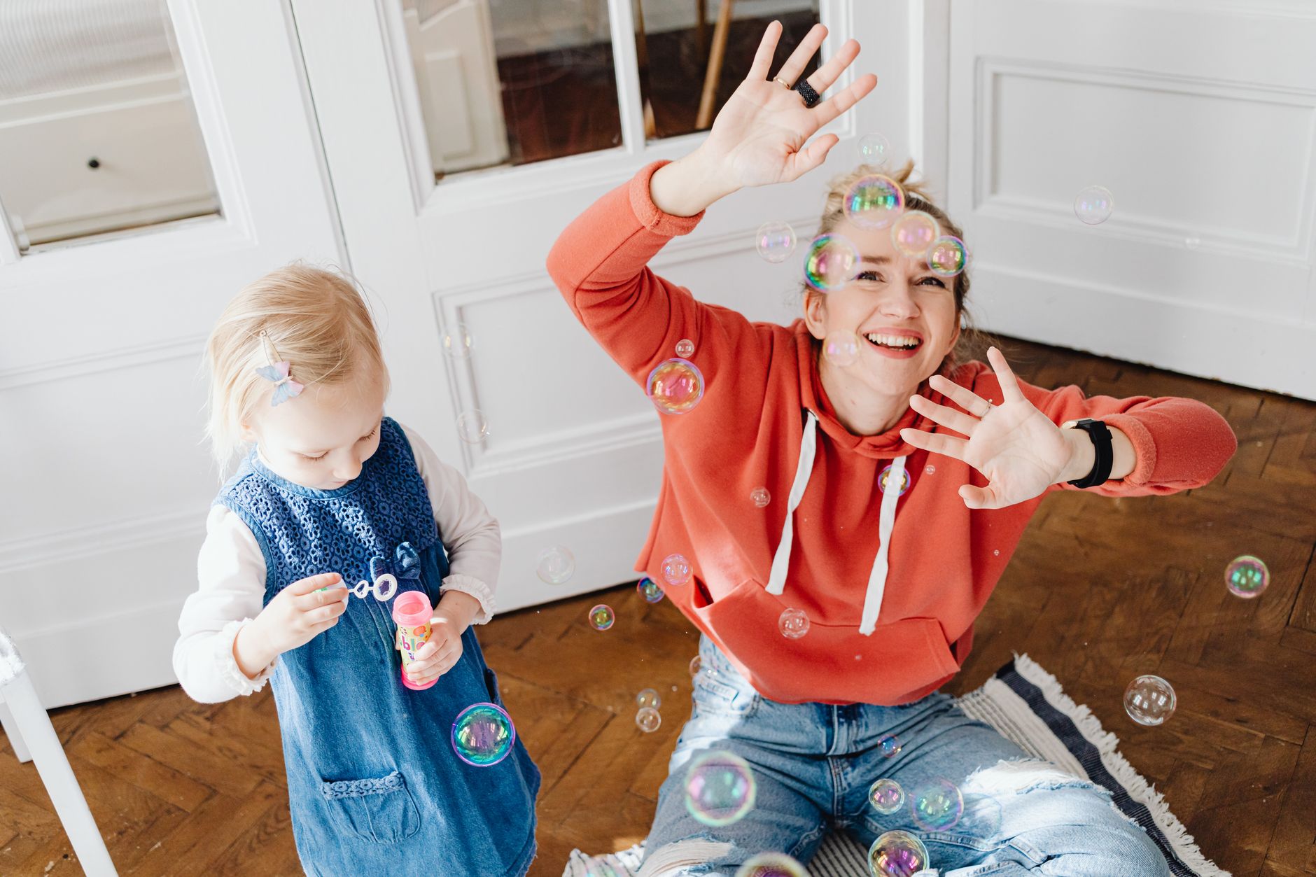 Joyful scene of a woman and child playing with bubbles indoors, capturing laughter and fun.